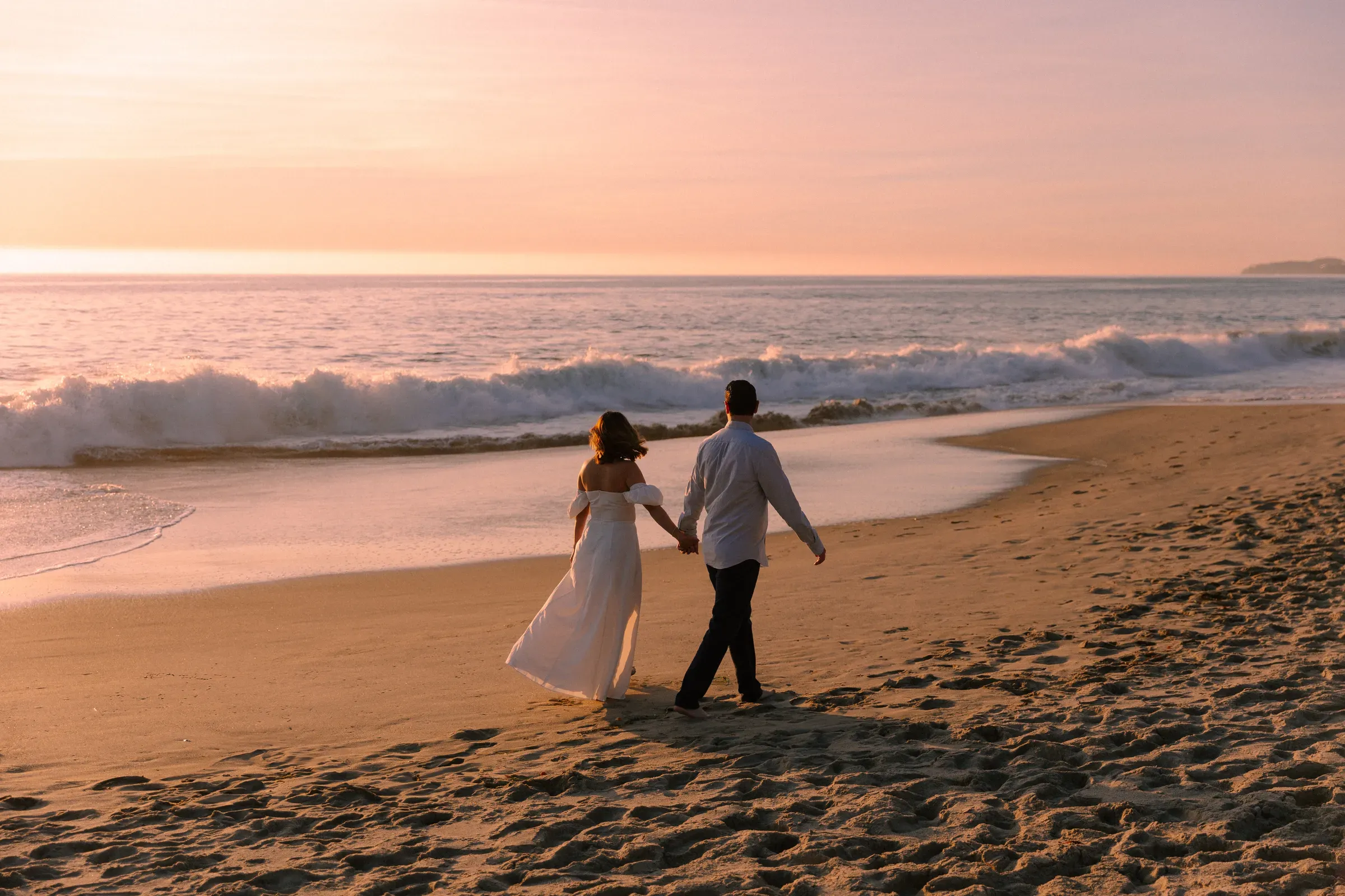 Engagement session — couple walking the shoreline at sunset