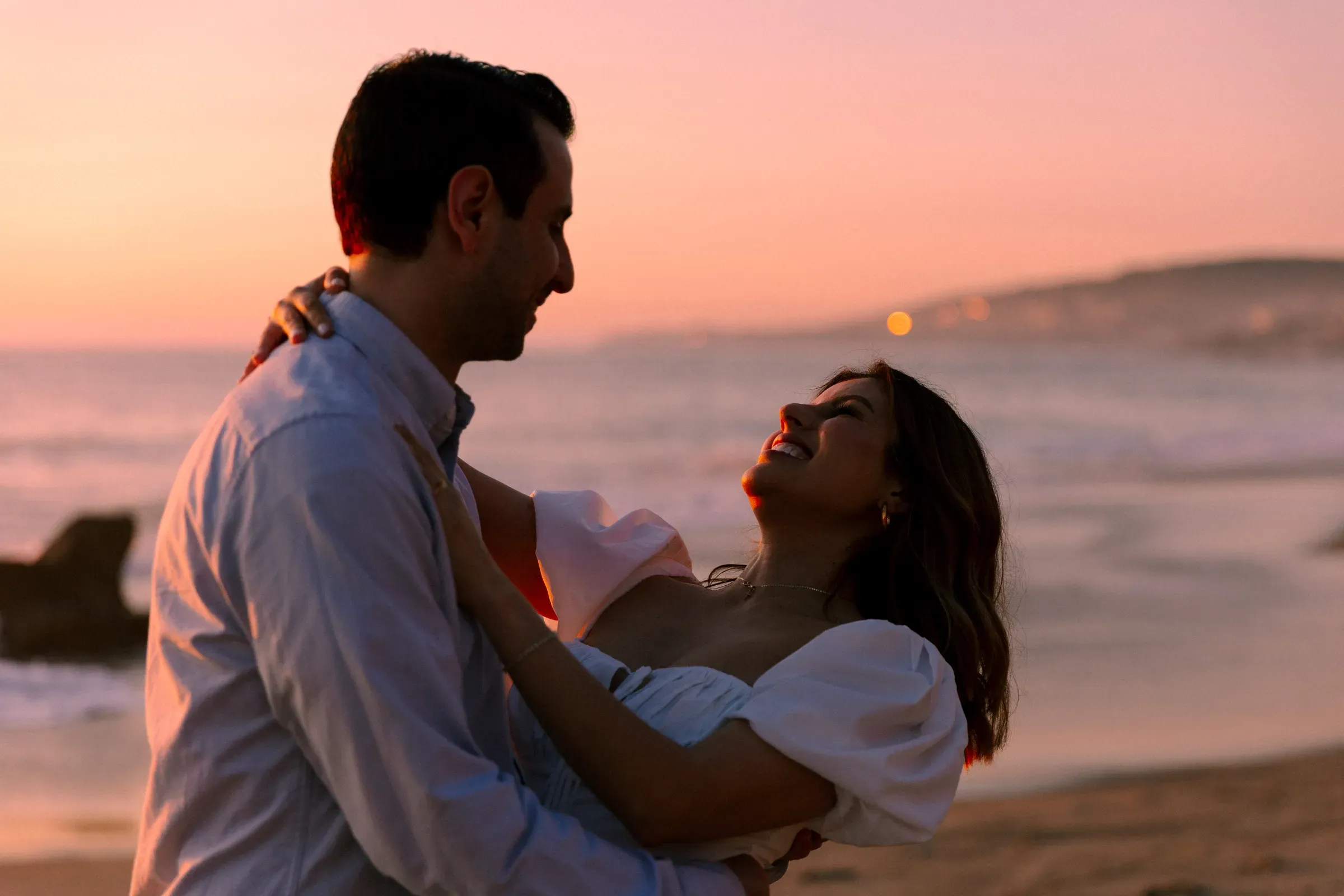 Engagement session — couple embracing on the beach at dusk