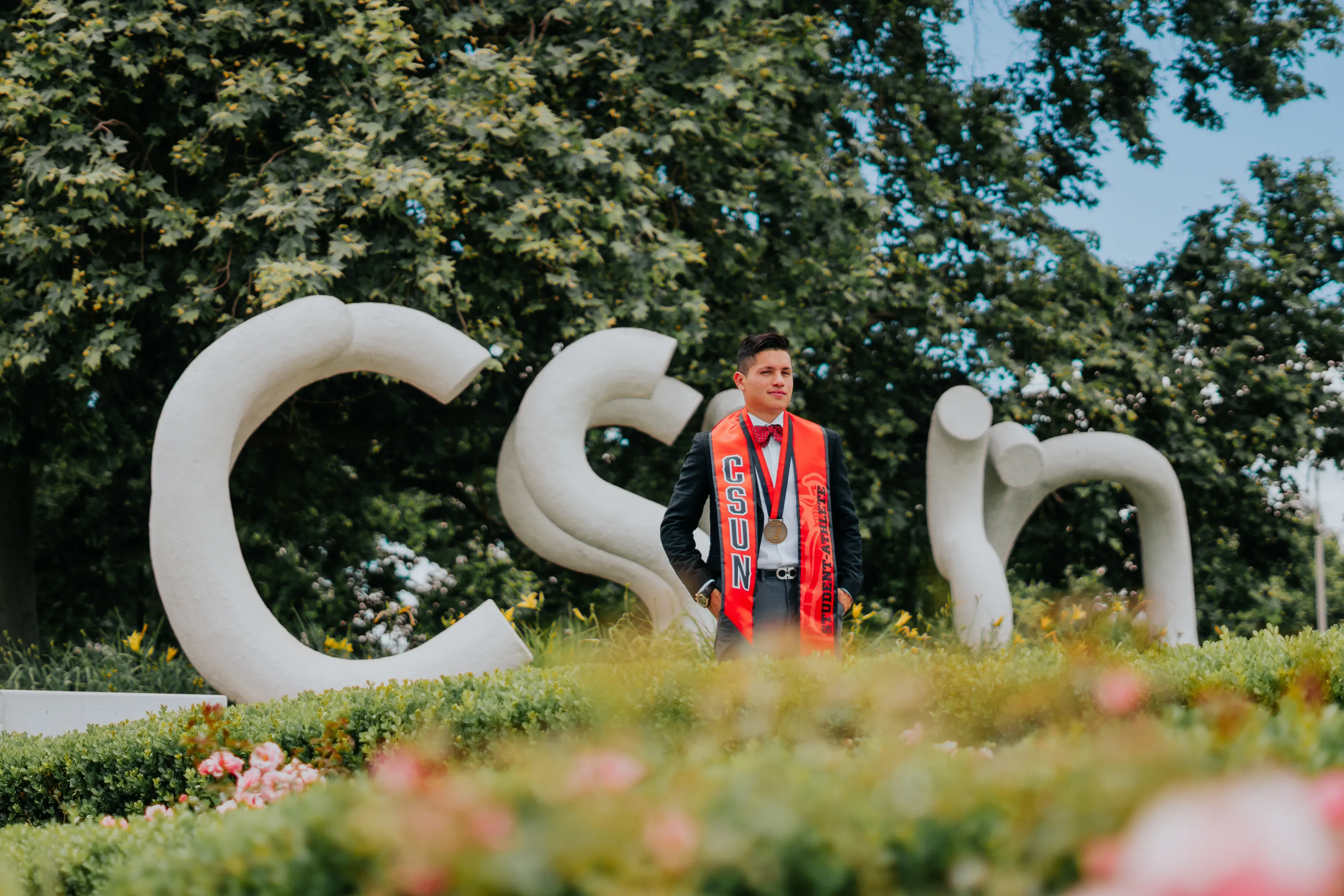 Cal State Fullerton graduation portrait framed by the campus sign and landscaping