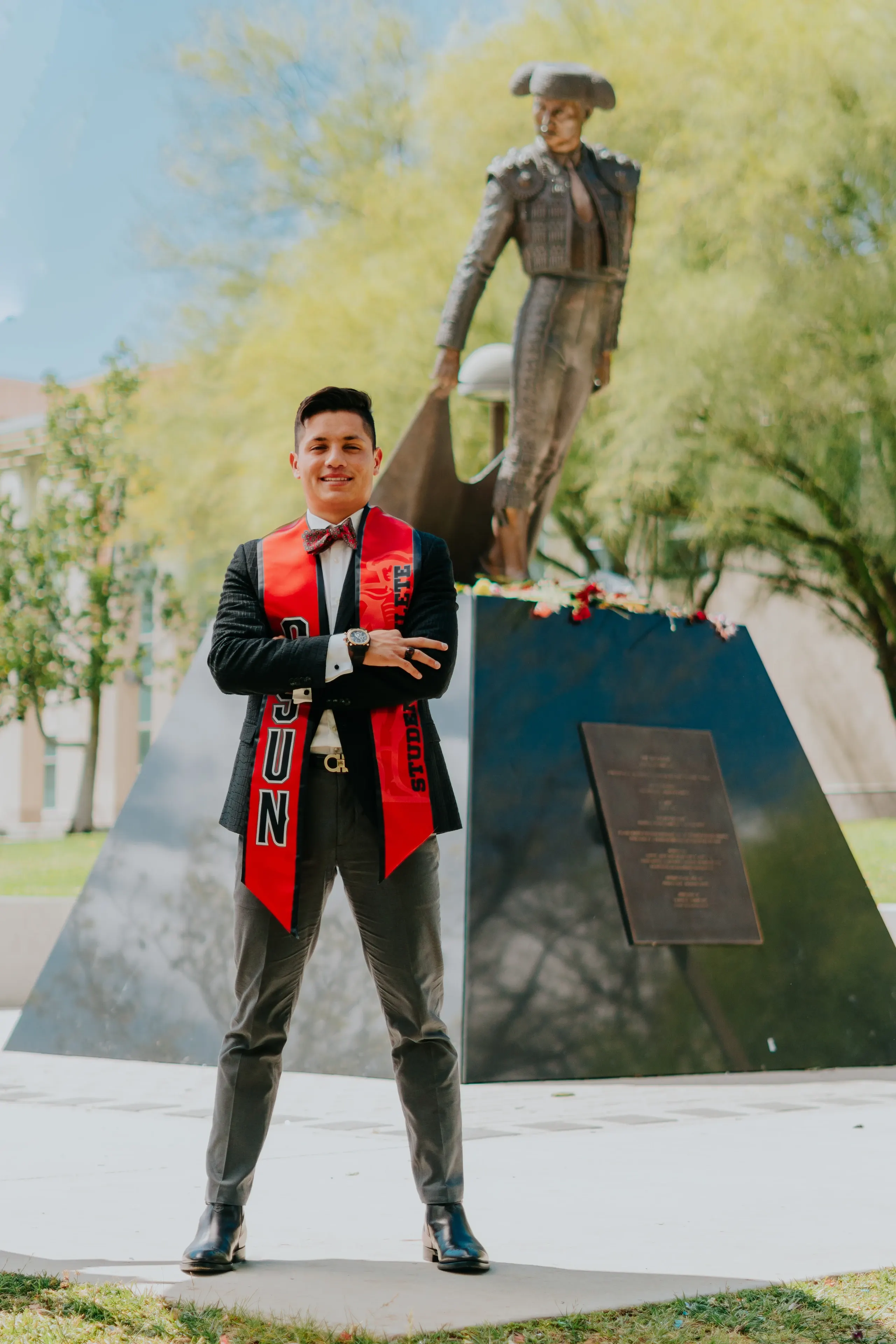 Cal State Fullerton graduate posing beside a campus monument