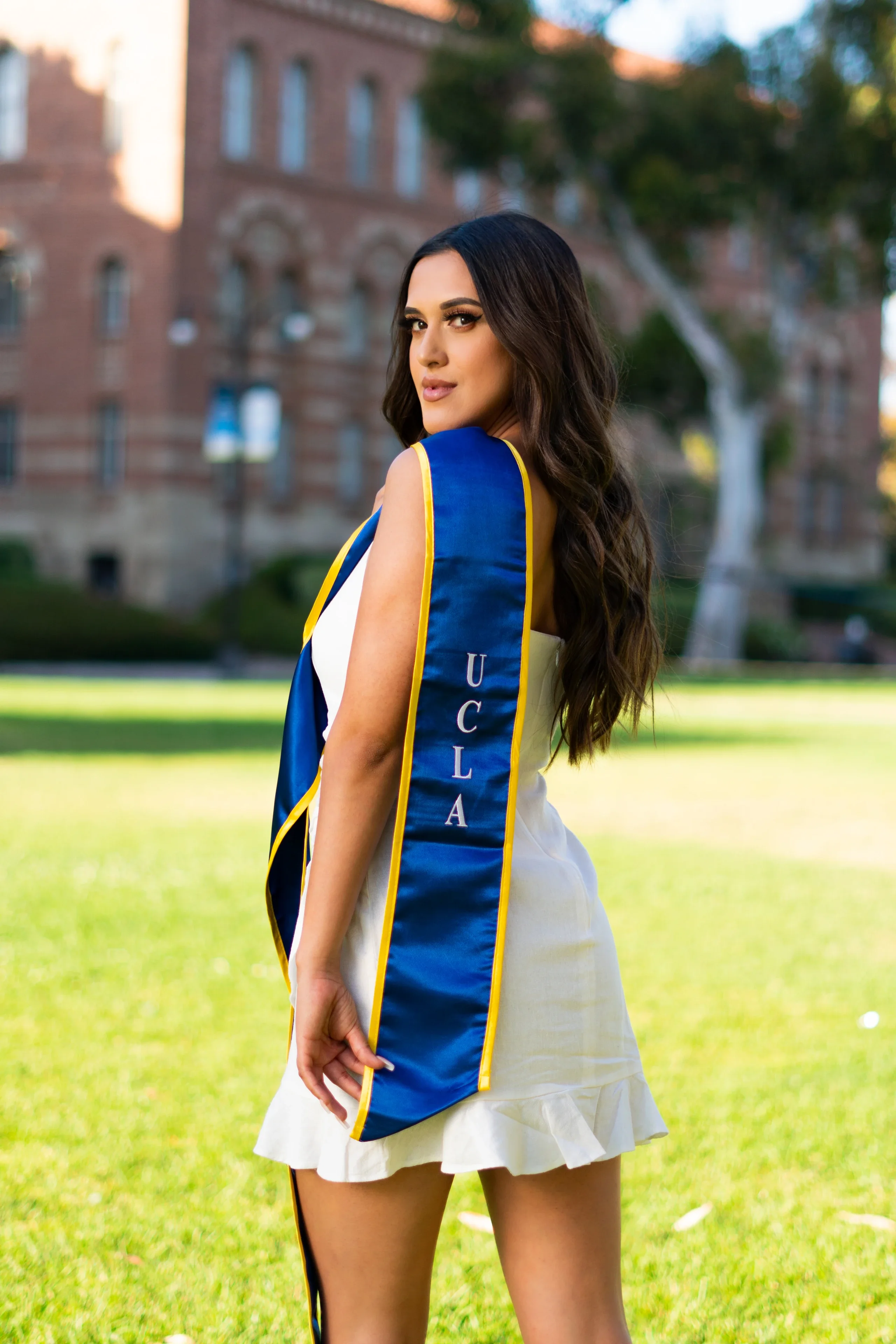 UCLA graduation portrait in a white dress and blue commencement stole