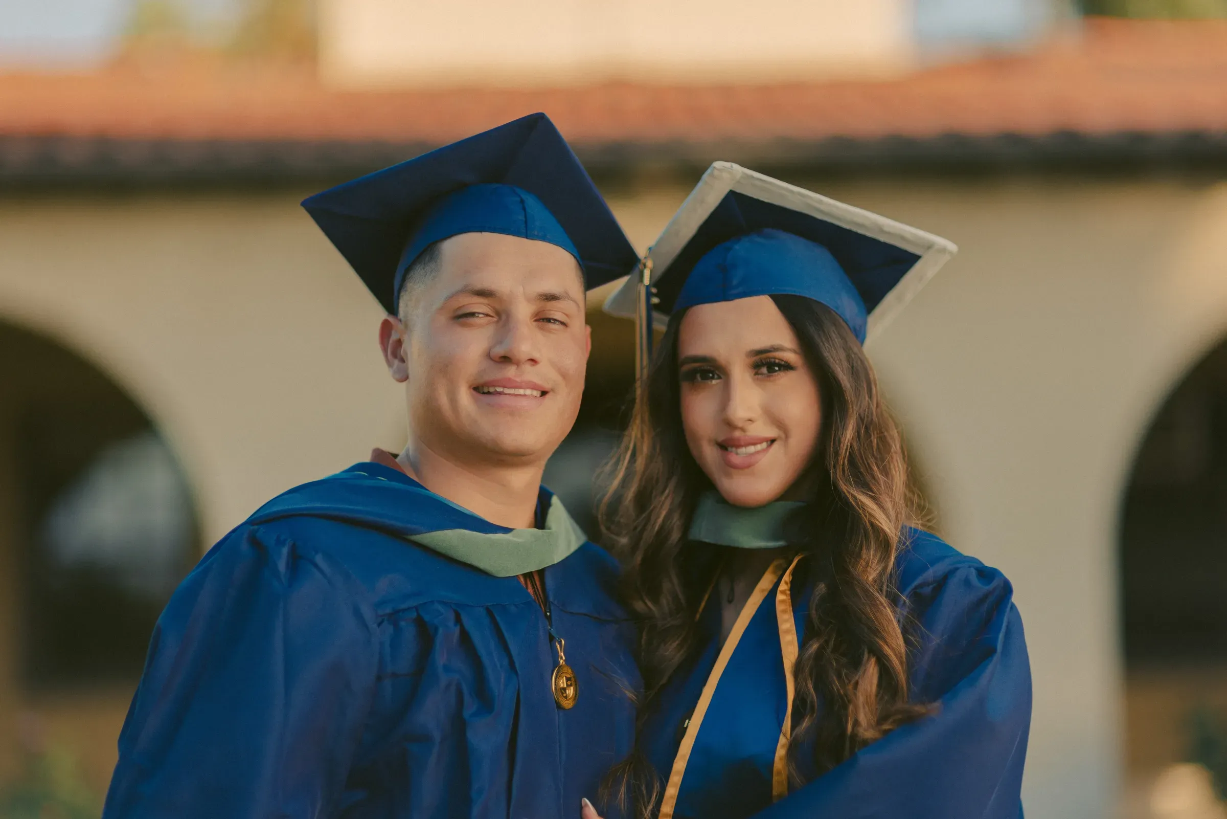 Two graduates celebrating in caps and gowns